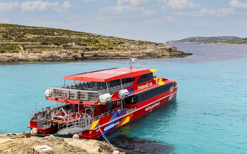Cruise ship docked at Blue Lagoon, Malta with clear turquoise water.