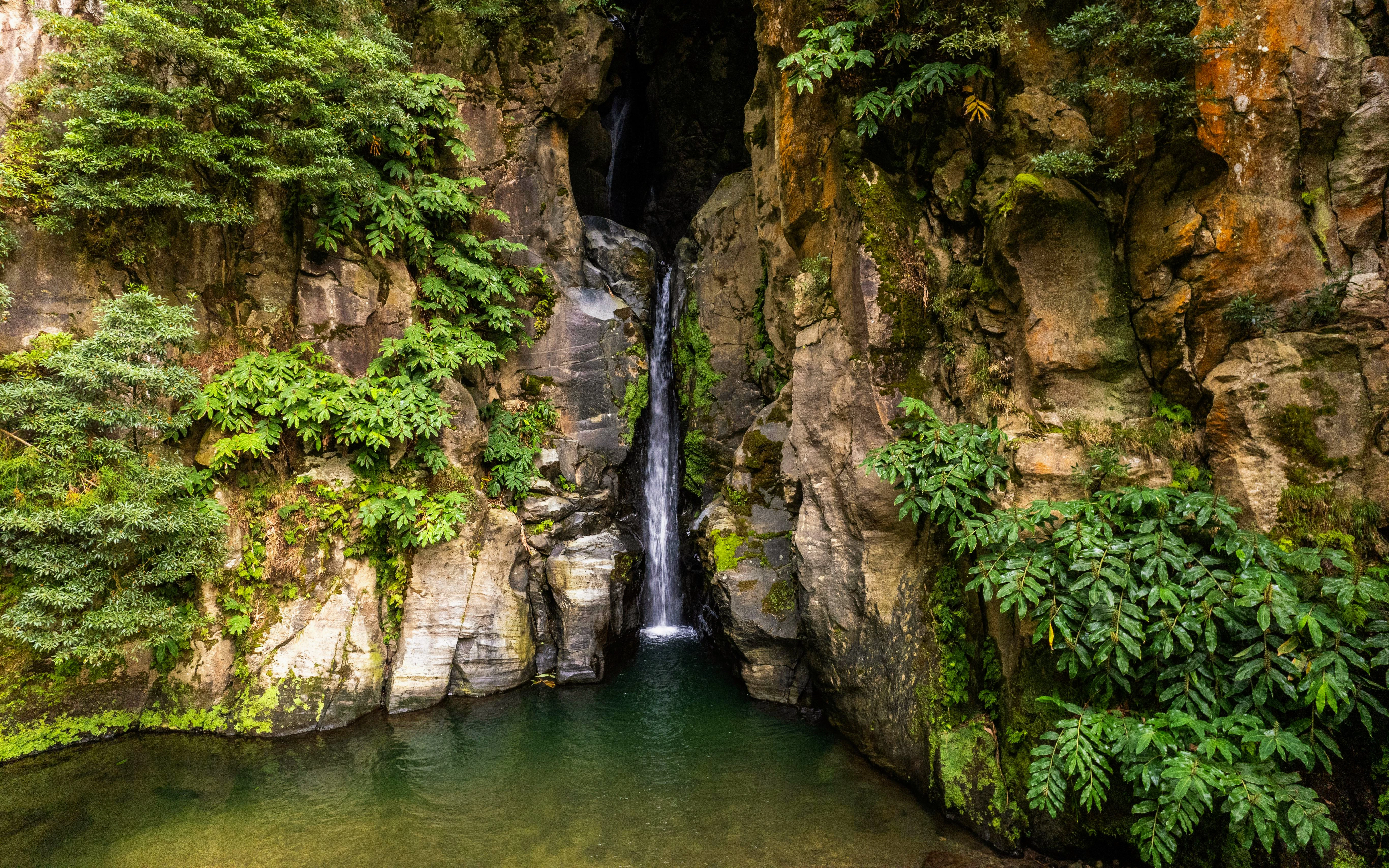 Salto do Cabrito Waterfall in Azores with Rocky Cliffs and Verdant Foliage