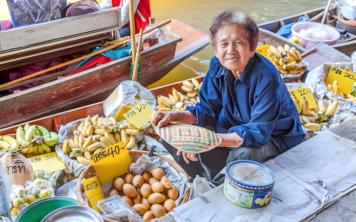 Vendor selling bananas and eggs at Damnoen Saduak Floating Market, Thailand.