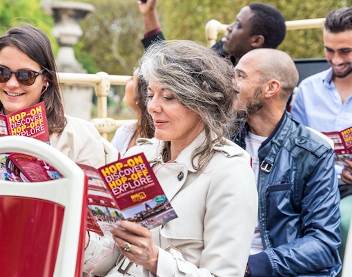 Tourists reading and listening to the audio guide in the open top Big Bus Paris Hop on Hop off