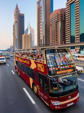 Open-top Big Bus tour in Dubai passing skyscrapers on Sheikh Zayed Road.