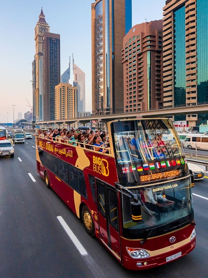 Open-top Big Bus tour in Dubai passing skyscrapers on Sheikh Zayed Road.