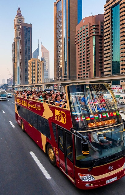 Open-top Big Bus tour in Dubai passing skyscrapers on Sheikh Zayed Road.