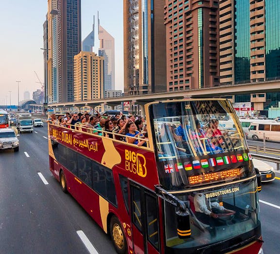 Open-top Big Bus tour in Dubai passing skyscrapers on Sheikh Zayed Road.