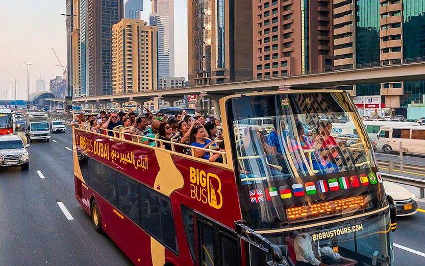 Open-top Big Bus tour in Dubai passing skyscrapers on Sheikh Zayed Road.
