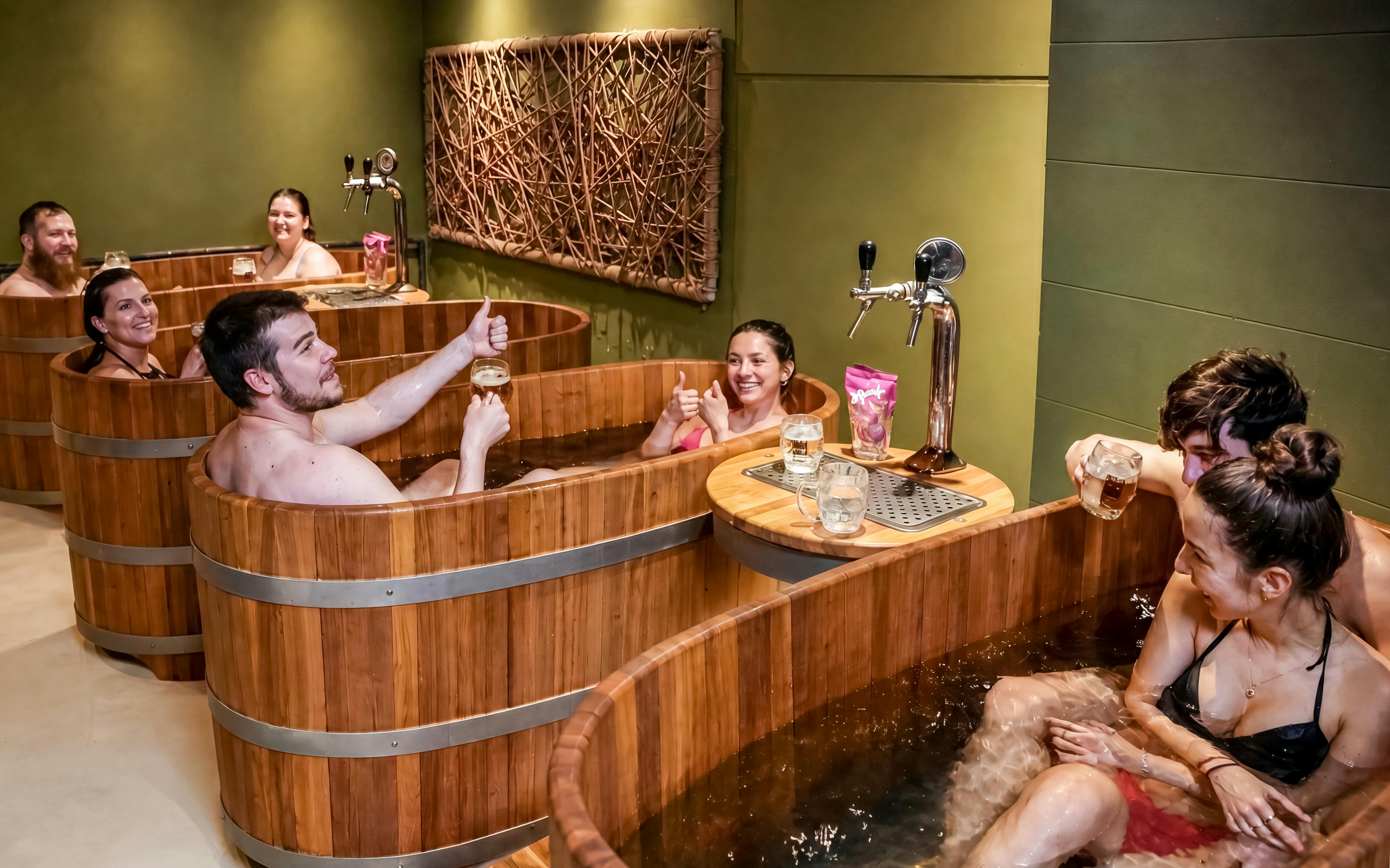 Guests enjoying beer spa in wooden tubs at Lukács Thermal Bath, Budapest.