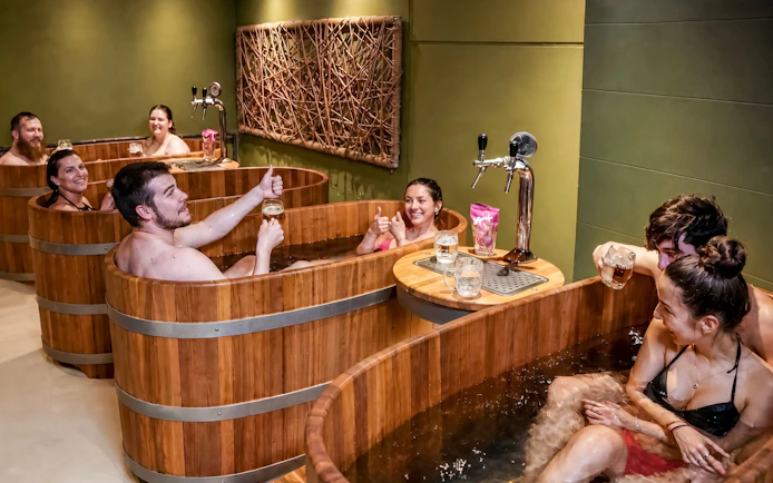 Guests enjoying beer spa in wooden tubs at Lukács Thermal Bath, Budapest.