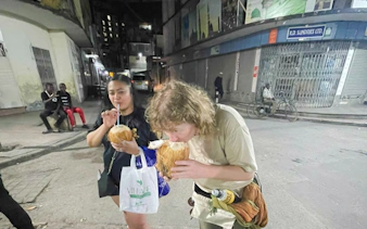 Tourists enjoying fresh coconuts during a night walk in Dar es Salaam Old Town, Zanzibar.