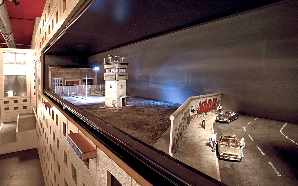DDR Museum Berlin exhibit featuring Berlin Wall and guard tower model.