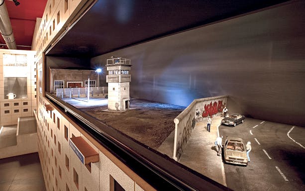DDR Museum Berlin exhibit featuring Berlin Wall and guard tower model.