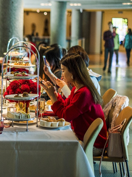 Guests enjoying high tea at National Gallery of Victoria with tiered trays of pastries.
