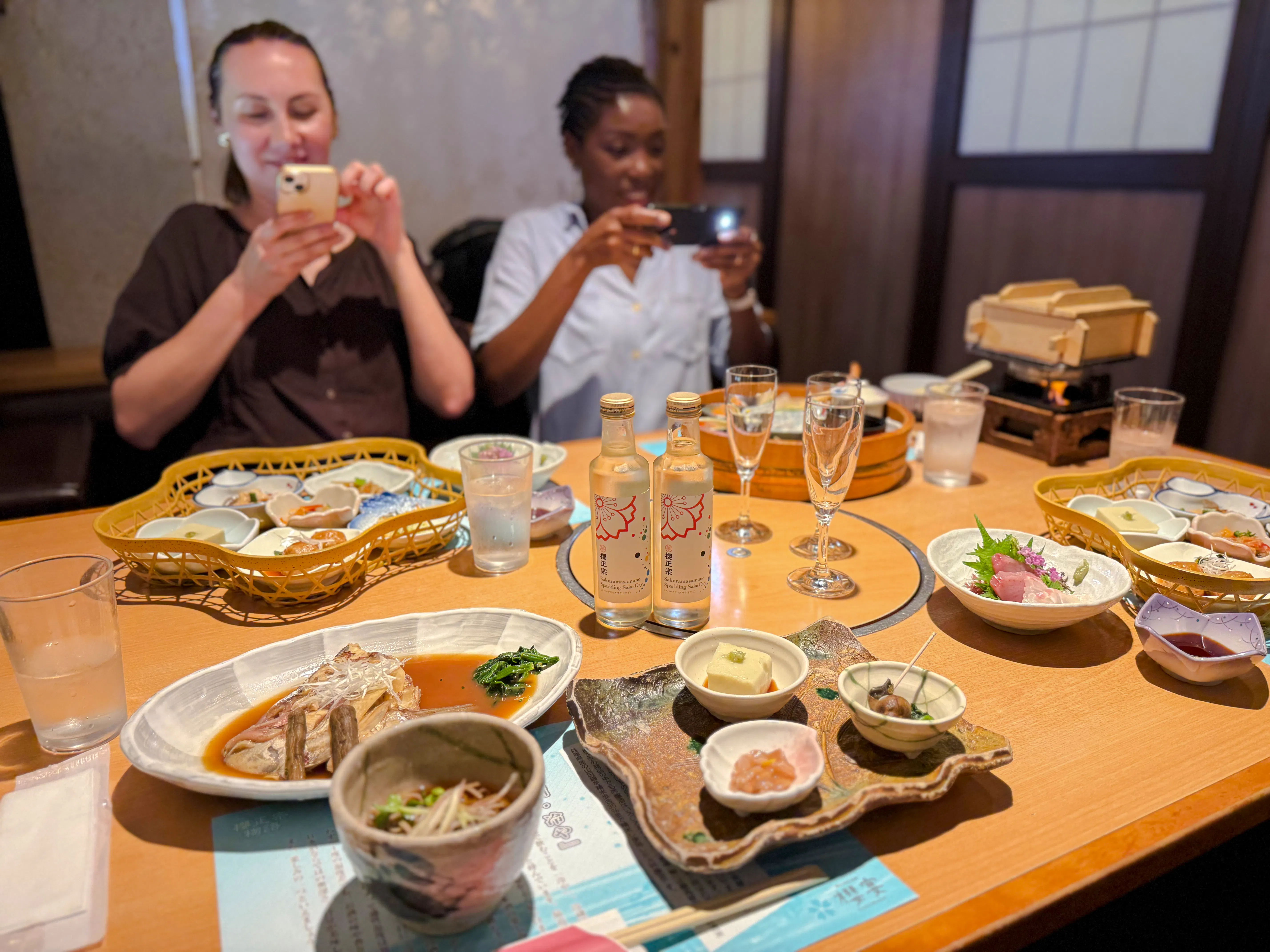 Kobe sake bottles and traditional Japanese lunch on a table during a brewery tour.