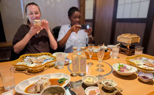 Kobe sake bottles and traditional Japanese lunch on a table during a brewery tour.