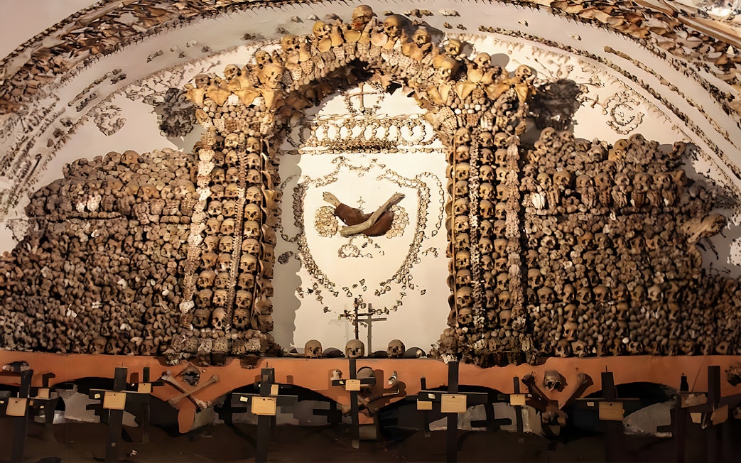 Skulls and bones arranged in a decorative pattern in a Roman Catacombs crypt.