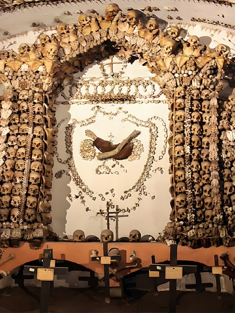 Skulls and bones arranged in a decorative pattern in a Roman Catacombs crypt.