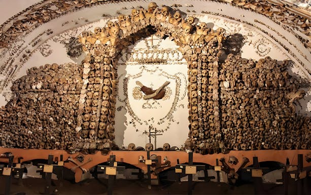 Skulls and bones arranged in a decorative pattern in a Roman Catacombs crypt.