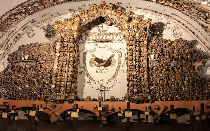 Skulls and bones arranged in a decorative pattern in a Roman Catacombs crypt.