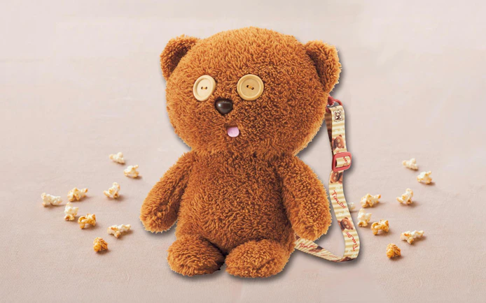 Plush bear with button eyes and popcorn pieces, USJ-themed strap attached.