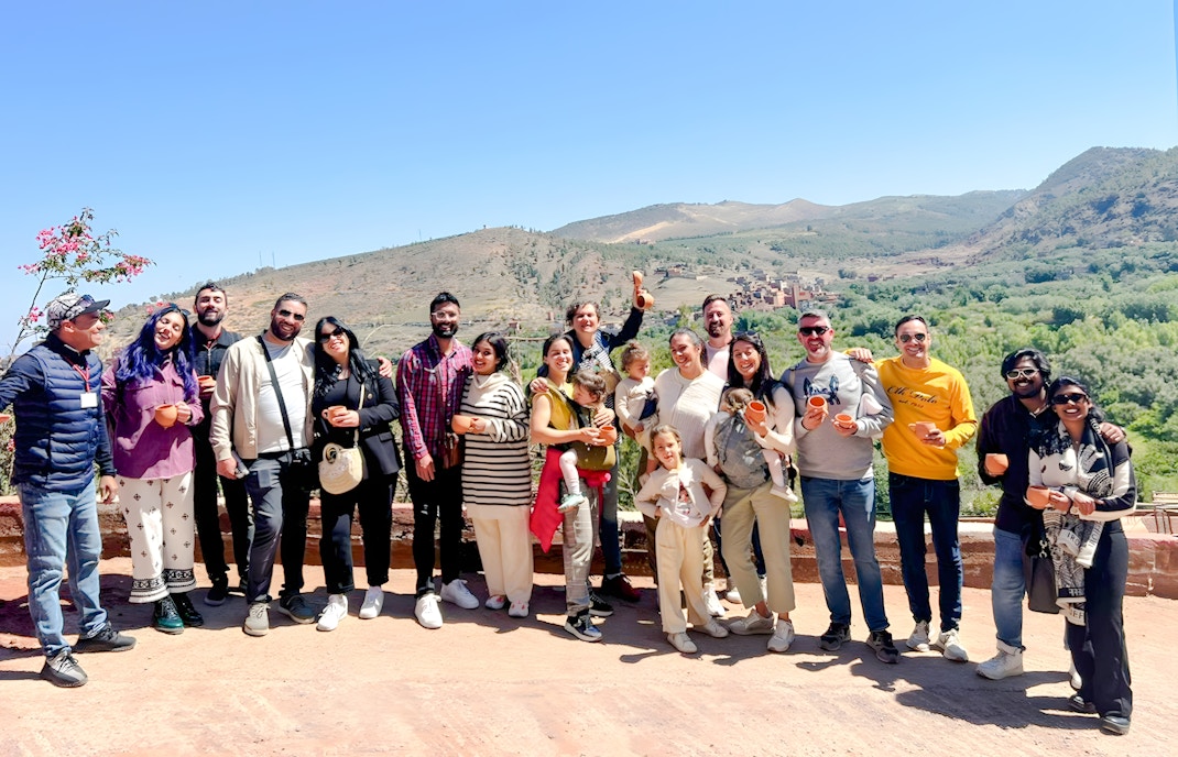 Group enjoying a scenic view in Ourika Valley, Morocco, with mountains in the background.
