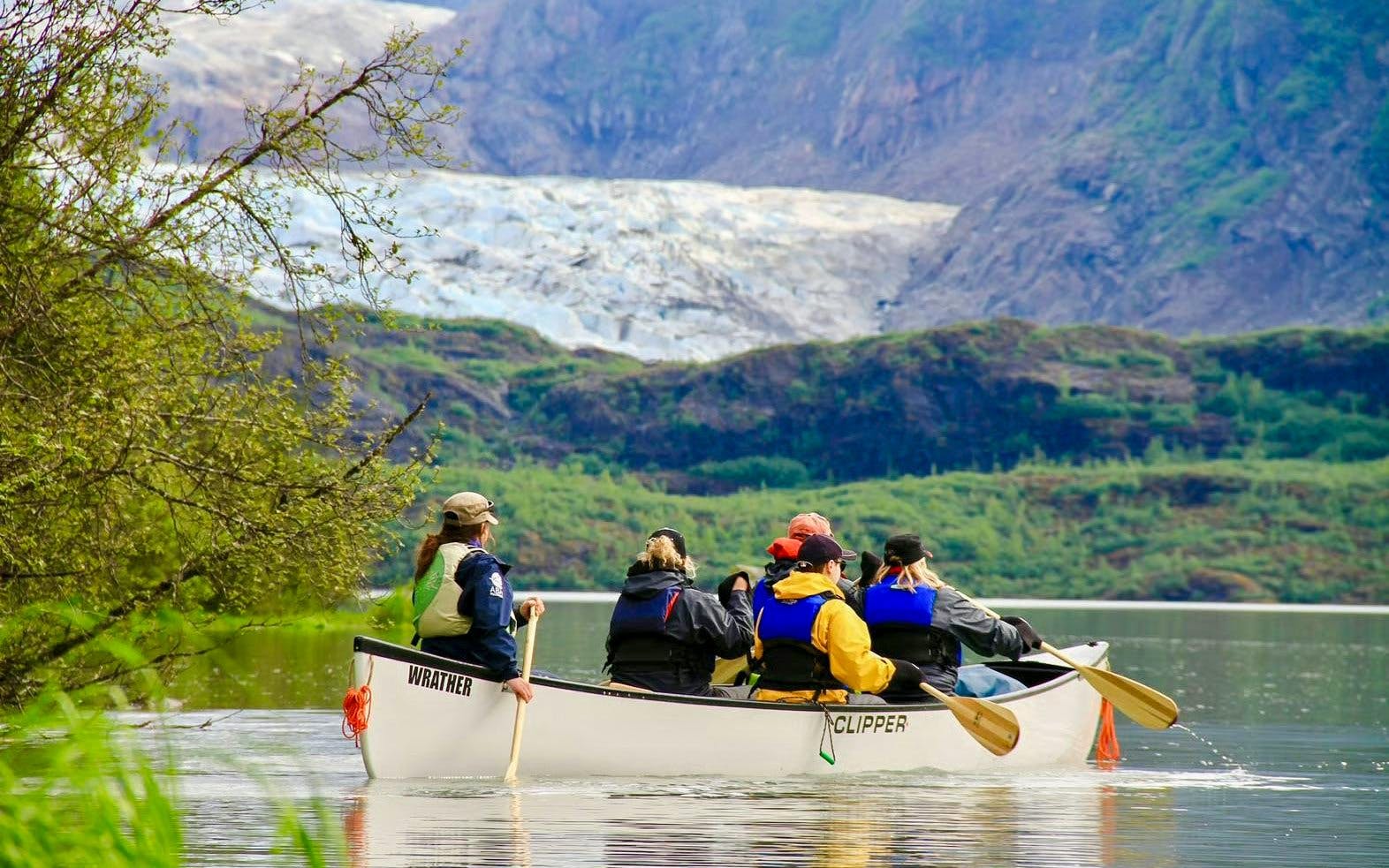 Canoe group paddling on lake with Mendenhall Glacier in background.