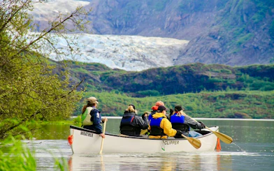 Canoe group paddling on lake with Mendenhall Glacier in background.