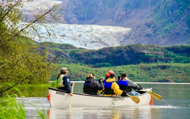 Canoe group paddling on lake with Mendenhall Glacier in background.