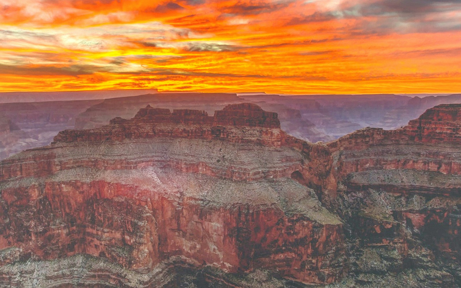 Tourists viewing the Grand Canyon West Rim from an observation point with a clear sky.