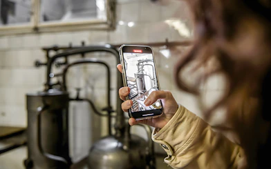 Person photographing historical pharmacy equipment in a cellar during a guided tour.