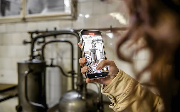 Person photographing historical pharmacy equipment in a cellar during a guided tour.