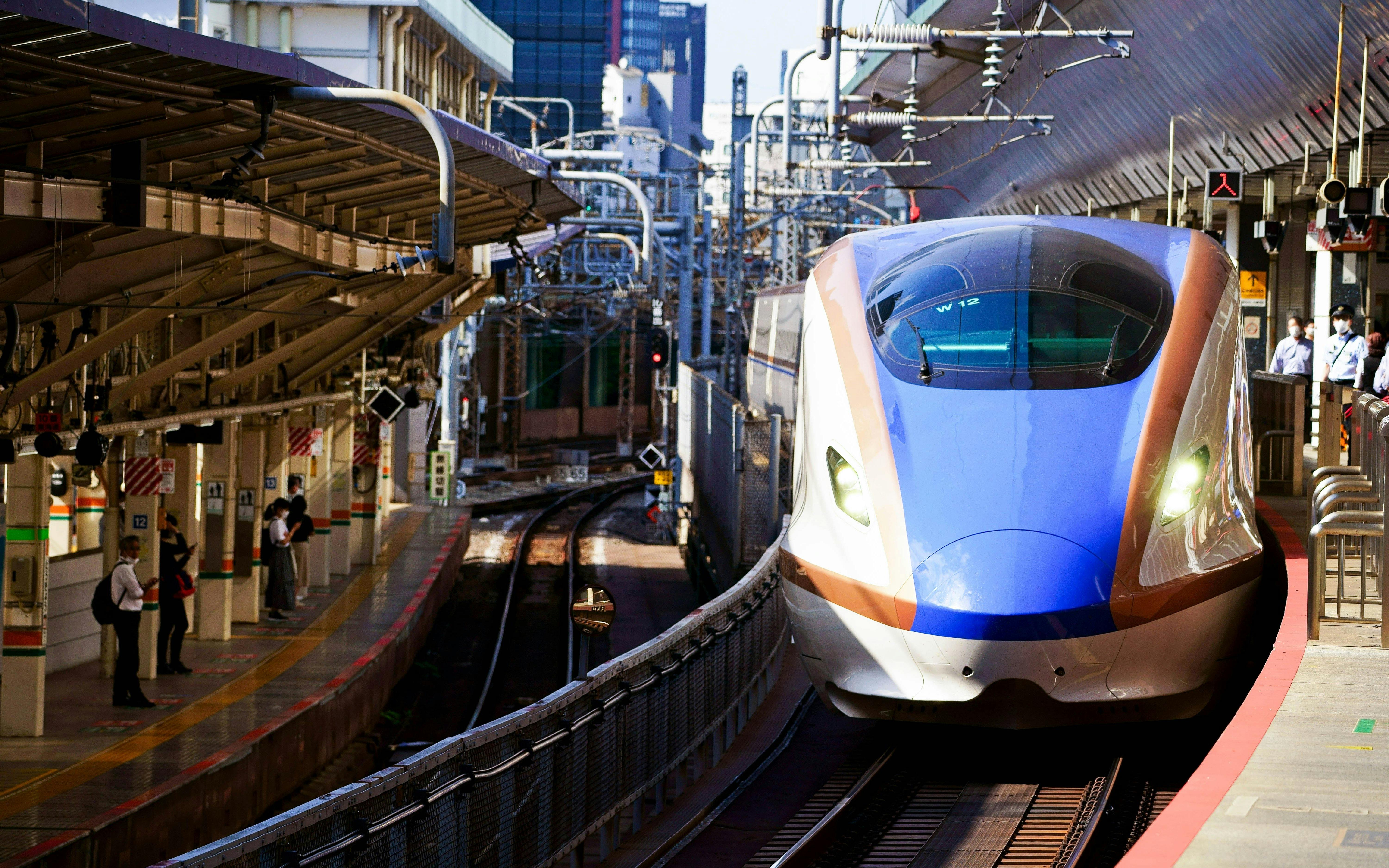 E7 series Shinkansen train arriving at Tokyo Station platform.