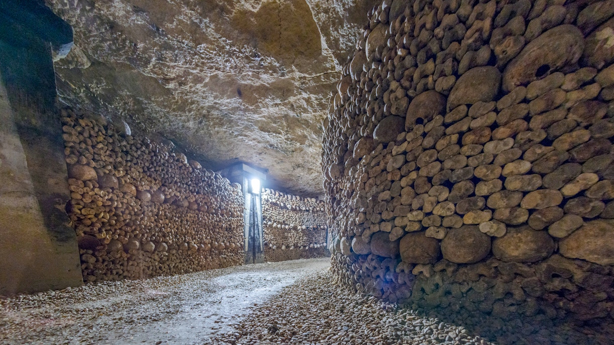Paris Catacombs corridor lined with skulls and bones.