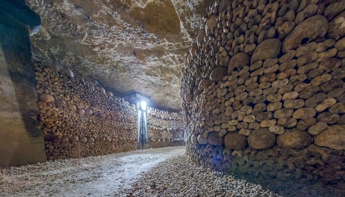 Paris Catacombs corridor lined with skulls and bones.