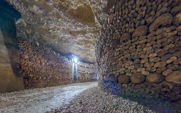 Paris Catacombs corridor lined with skulls and bones.