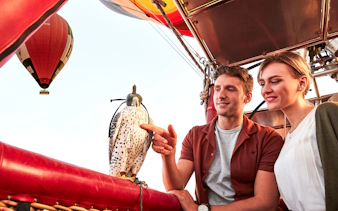 Hot air balloon ride with falconry experience, featuring a couple observing a falcon in the basket.