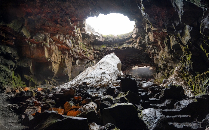 Raufarhólshellir Lava Cave interior with rock formations and natural light, Iceland.