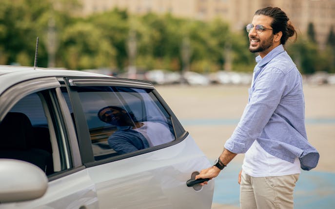 Man opening car door for private airport transfer in New York.