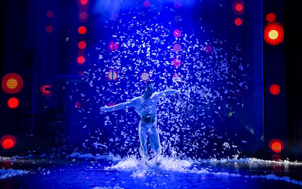 Performer surrounded by feathers on stage during 90s Forever show.