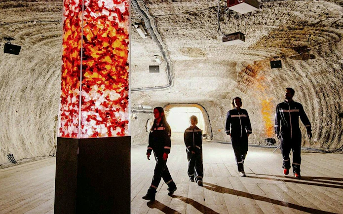 Guests walking inside Berchtesgaden Salt Mine with illuminated salt pillar.