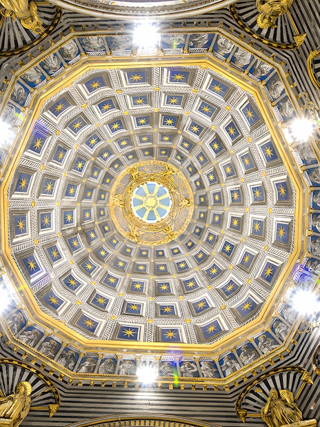 Siena Duomo dome interior with intricate gold and blue star patterns.