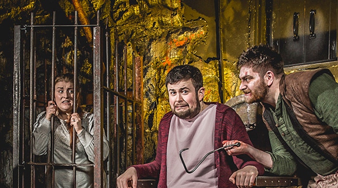 Man in stocks with actor holding tool at Edinburgh Dungeon.