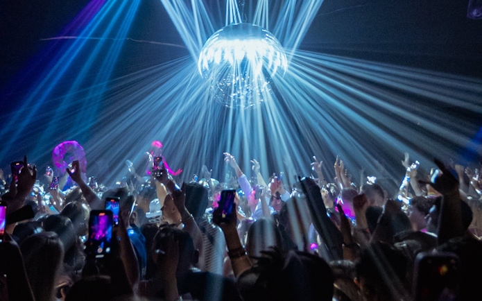 DJ performing at La Troya Club Chinois, Ibiza with crowd and light show.