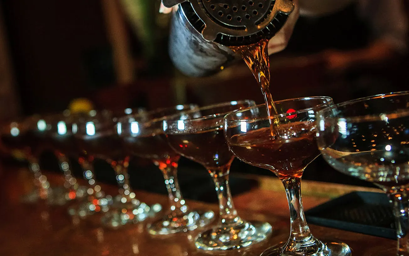 Bartender pouring cocktails during New Orleans Craft Cocktail Walking Tour.