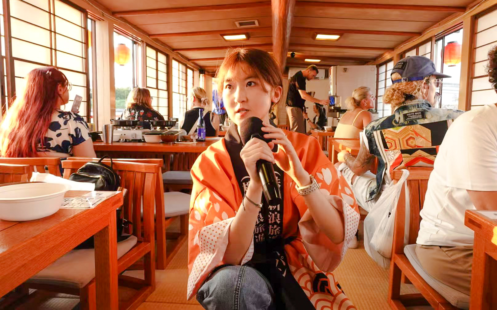 Tourist enjoying Yakatabune Hot Pot Cruise experience with microphone on traditional boat.