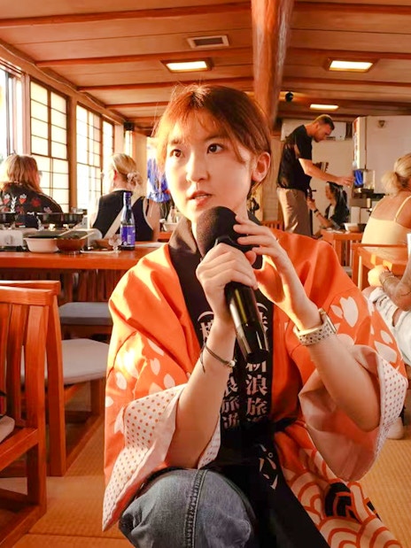 Tourist enjoying Yakatabune Hot Pot Cruise experience with microphone on traditional boat.