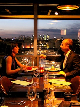 Dining couple with Eiffel Tower view in Paris restaurant.