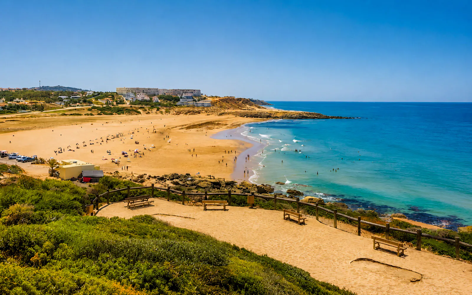 Tangier Beach with visitors swimming and sunbathing, surrounded by coastal landscape.