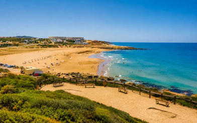 Tangier Beach with visitors swimming and sunbathing, surrounded by coastal landscape.