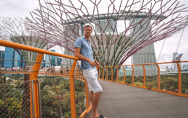 Man on walkway at Gardens by the Bay with Marina Bay Sands in background, Singapore.