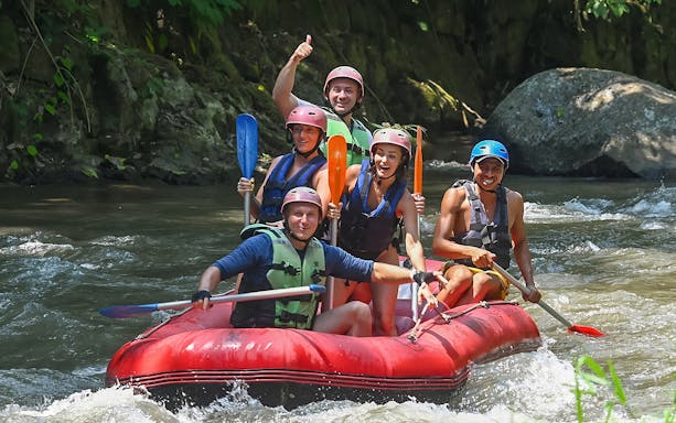 Group rafting on Ayung River in Ubud, navigating rapids with paddles.