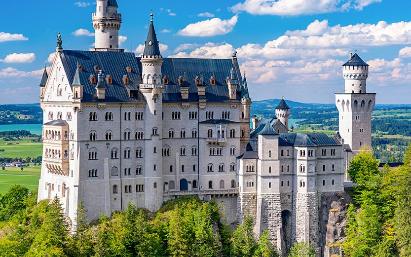 Neuschwanstein Castle in Bavaria, Germany, surrounded by lush green forest.